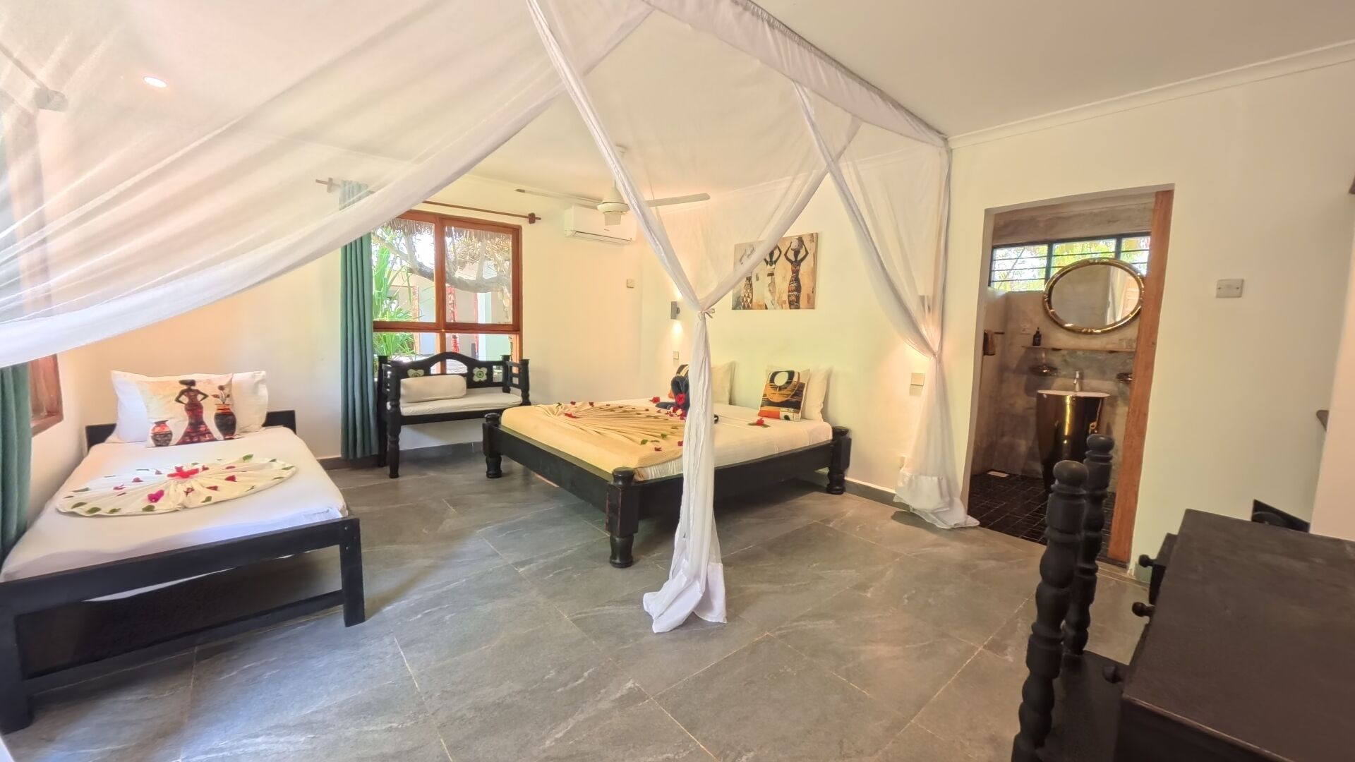 Een slaapkamer met een hemelbed, een dagbed, een kleine tafel en een spiegel.