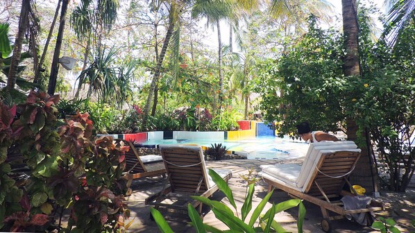 Una piscina al aire libre, sillones reclinables de piscina