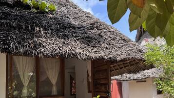 Una casa tradicional con techo de paja, puerta y ventanas de madera, rodeada de follaje.