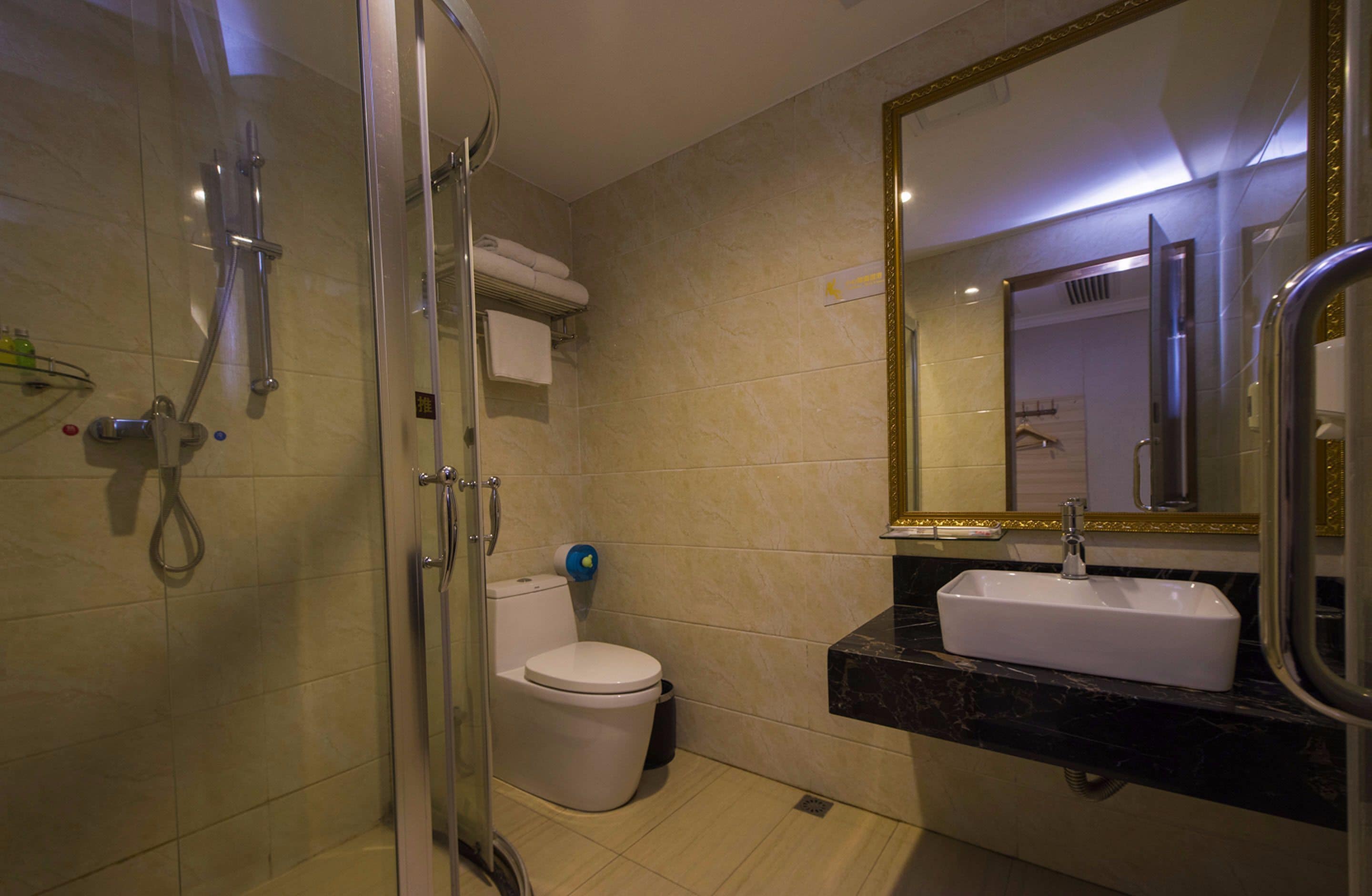 Un baño moderno con ducha envuelta en vidrio, inodoro blanco y lavamanos con encimera de mármol.