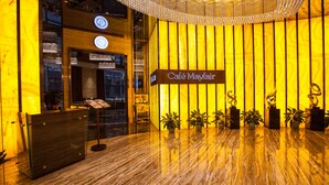 Un área de recepción con suelo de mármol, un mostrador de recepción y un letrero que dice "Café Mayfair".