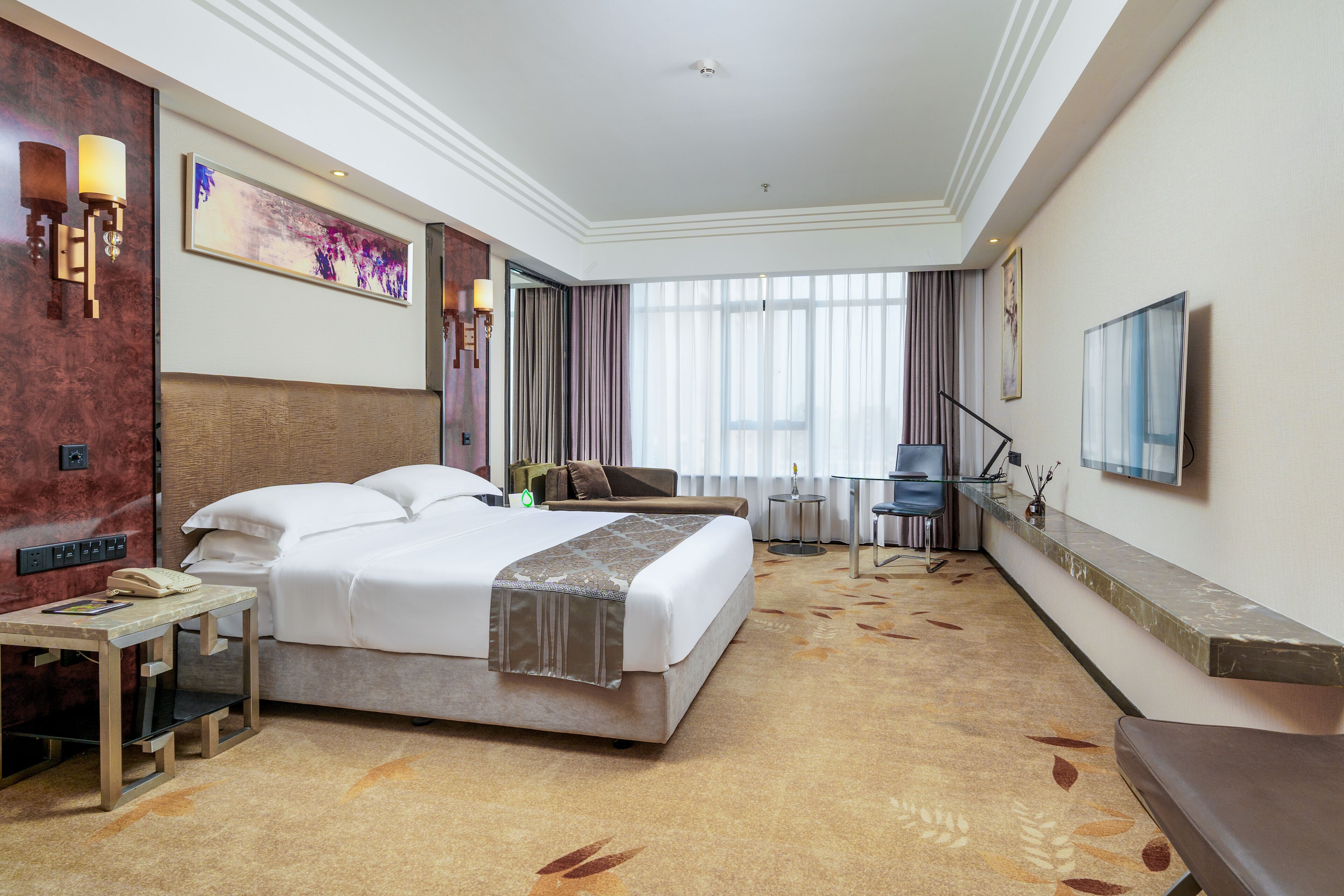 Habitación de hotel con una cama grande, un escritorio con teléfono, una silla y un televisor montado en la pared.