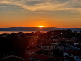 Un pueblo costero al atardecer, con edificios y una masa de agua en primer plano.