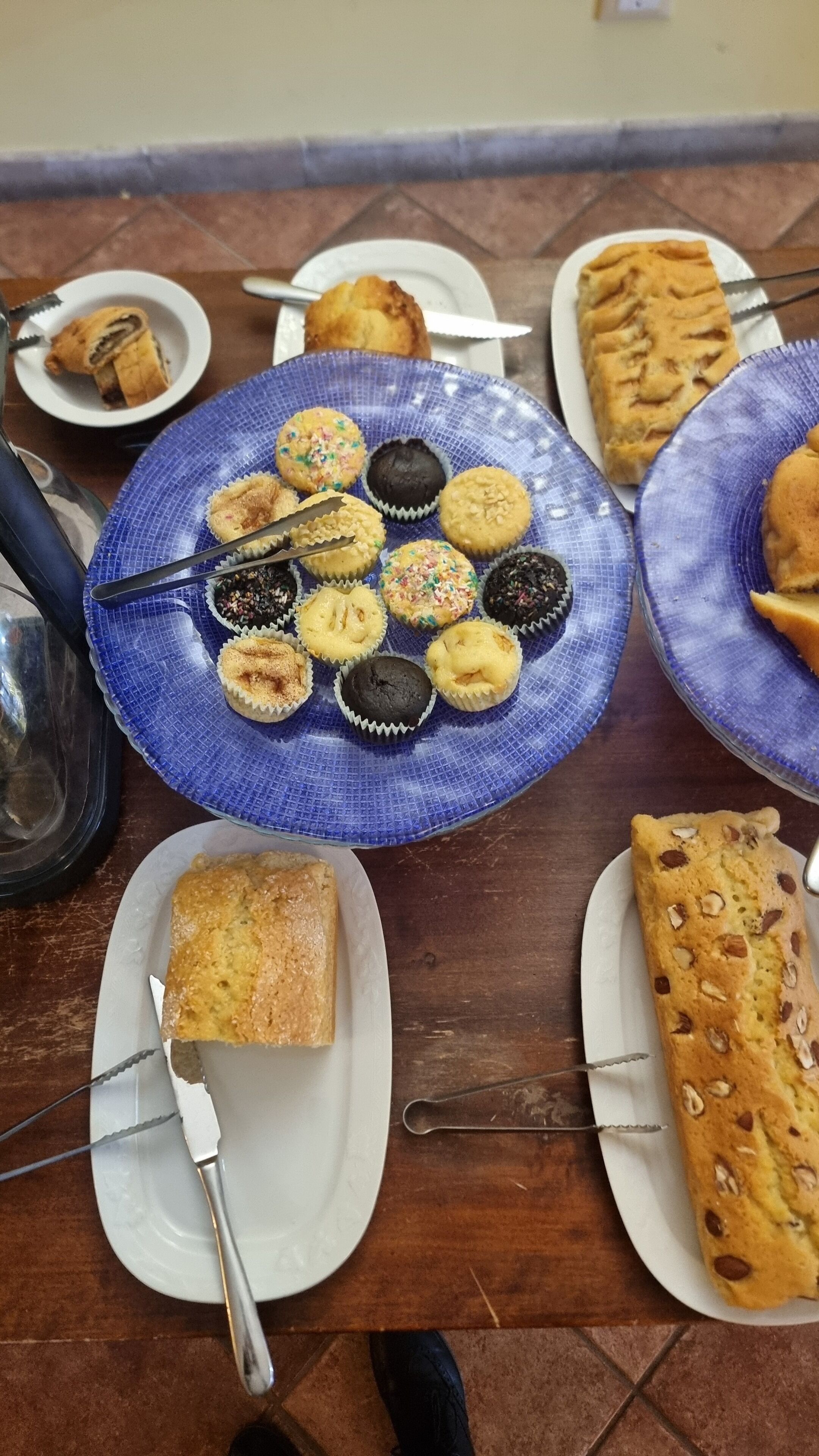 A table with various baked goods including muffins, cookies, and a loaf of bread.