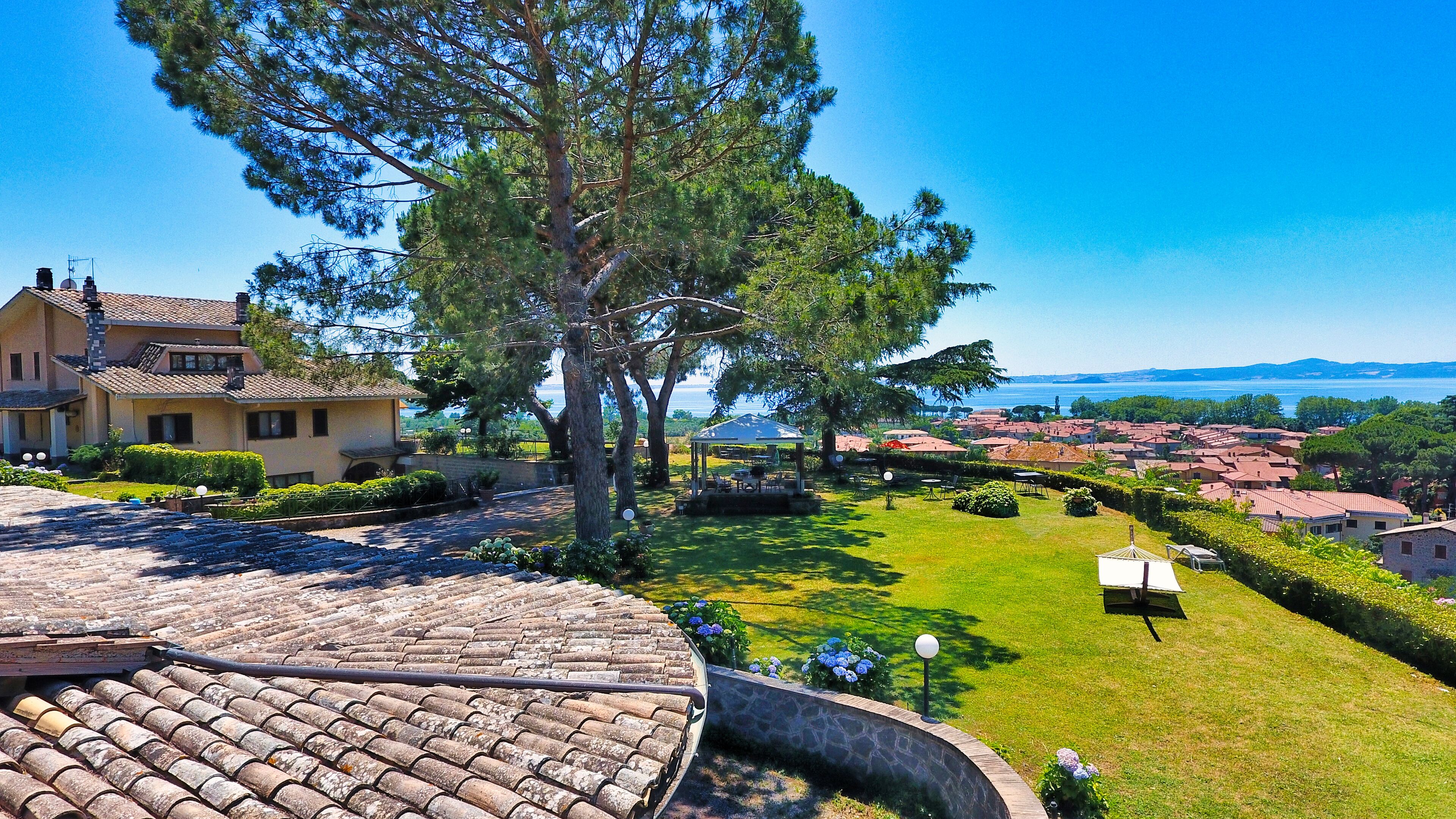 Una villa con techo de tejas, un jardín con un mirador y vistas a un pueblo costero.
