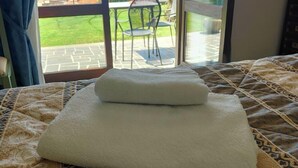 A bed with a patterned bedspread and two folded white towels. - Le vigne (Bolsena)