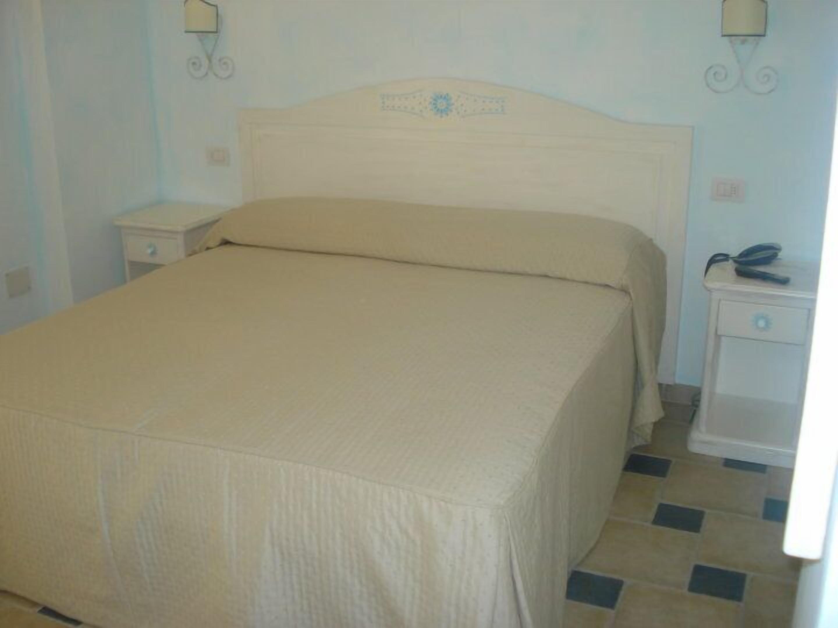 Ein Schlafzimmer mit einem Bett, Nachttischen und einer Wandleuchte.