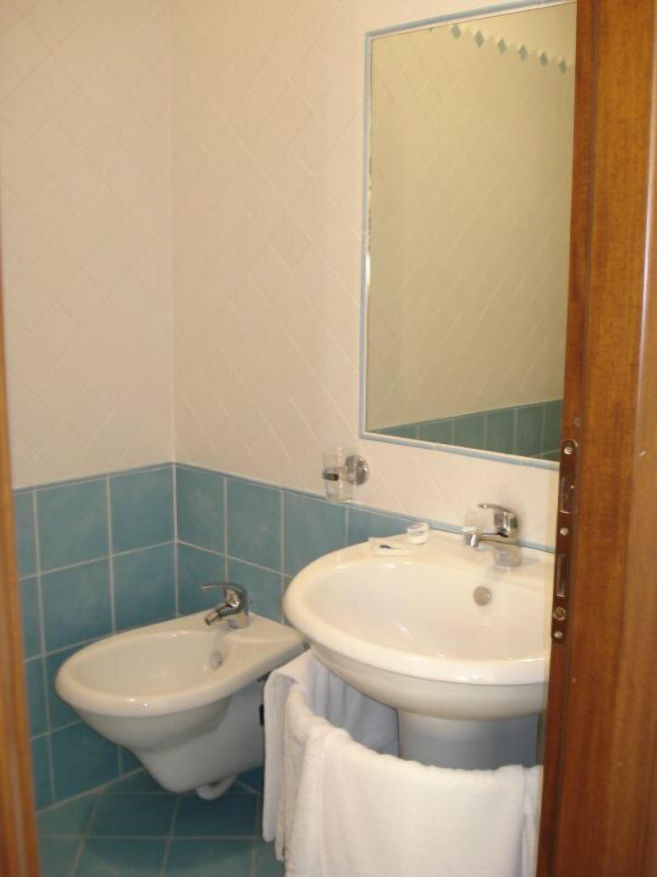A bathroom with a bidet, a sink, and a mirror.