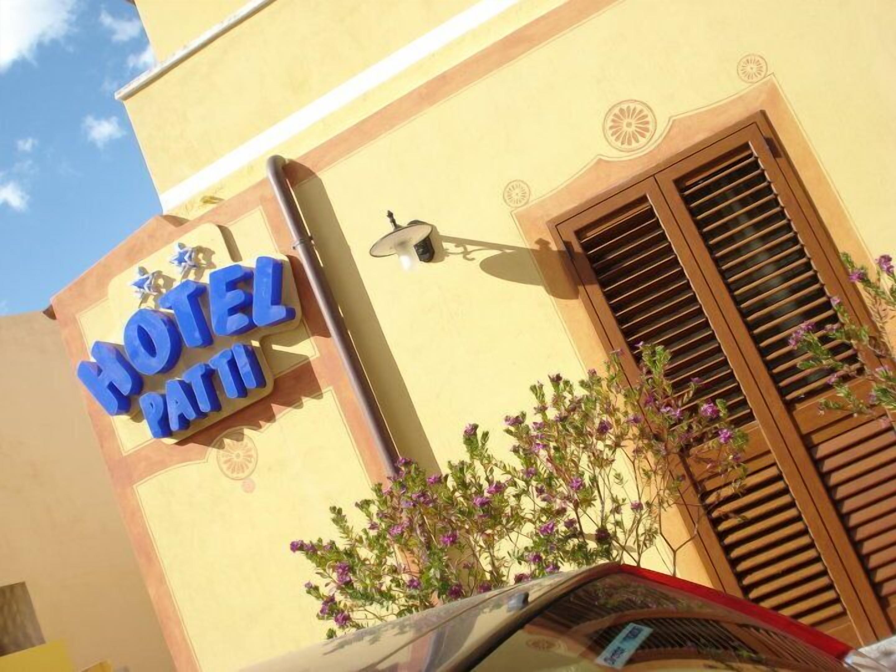 A hotel sign with a decorative design and a window with shutters.