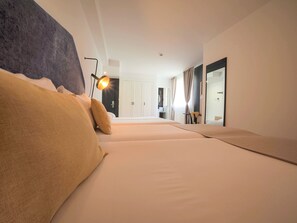A modern hotel room with a large bed, a desk, and a mirror.
