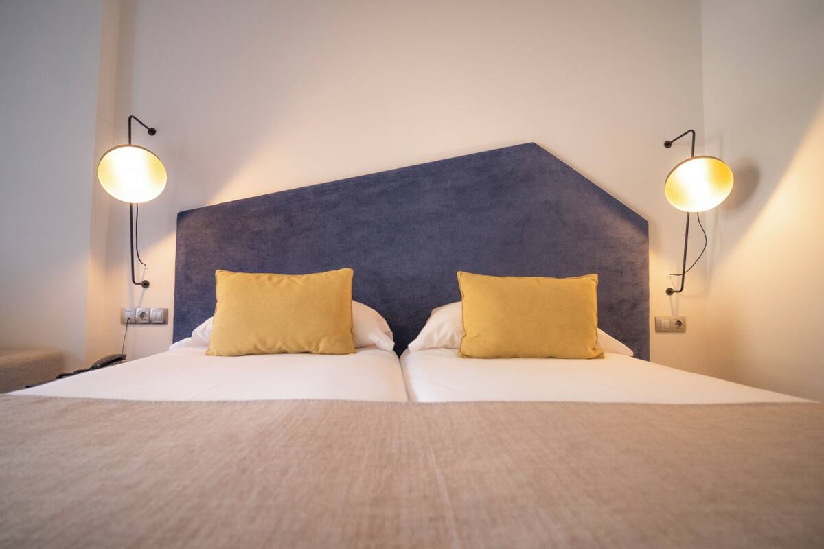 A double bed with a dark headboard and two bedside lamps.
