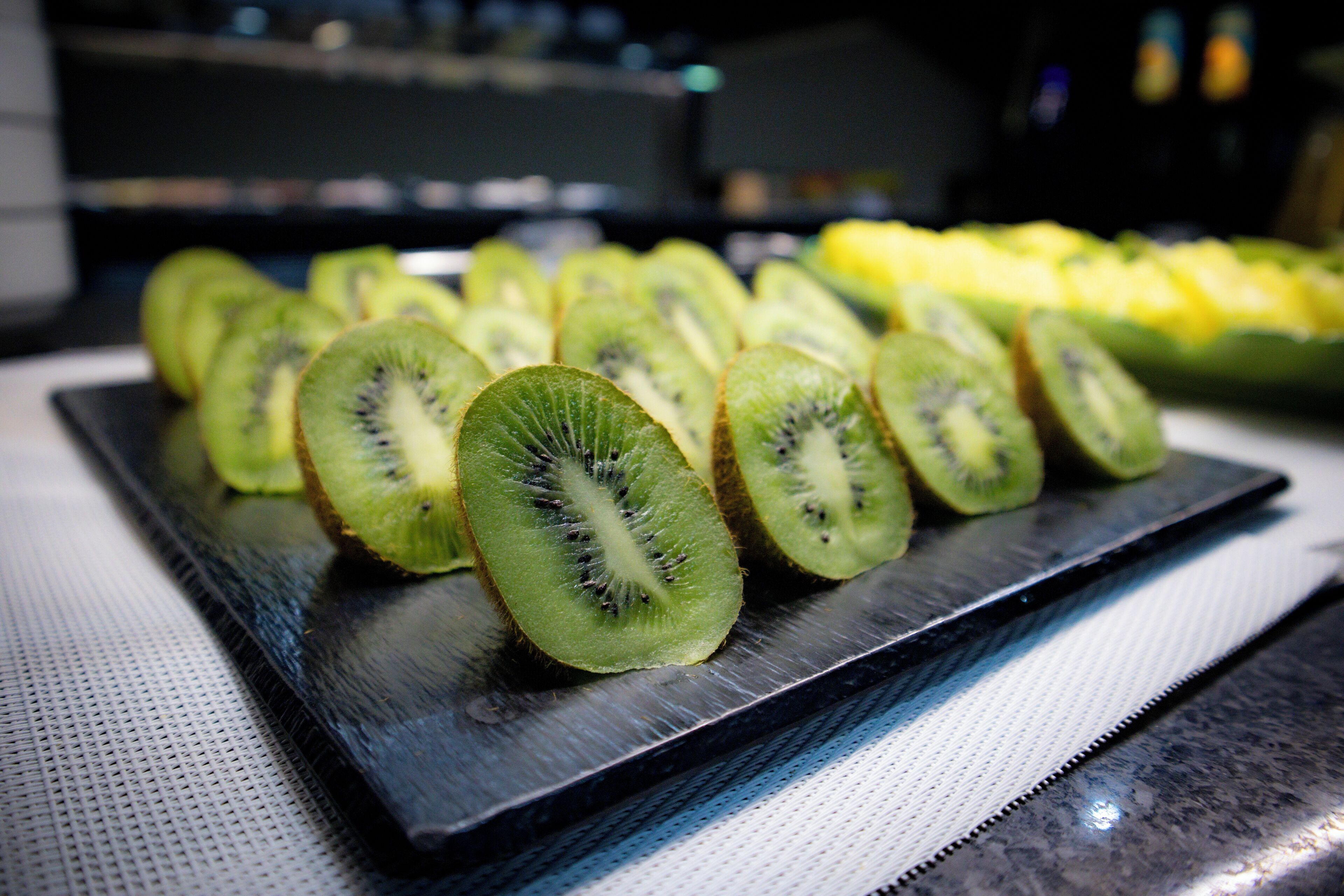 A tray of sliced kiwi fruit on a black plate.