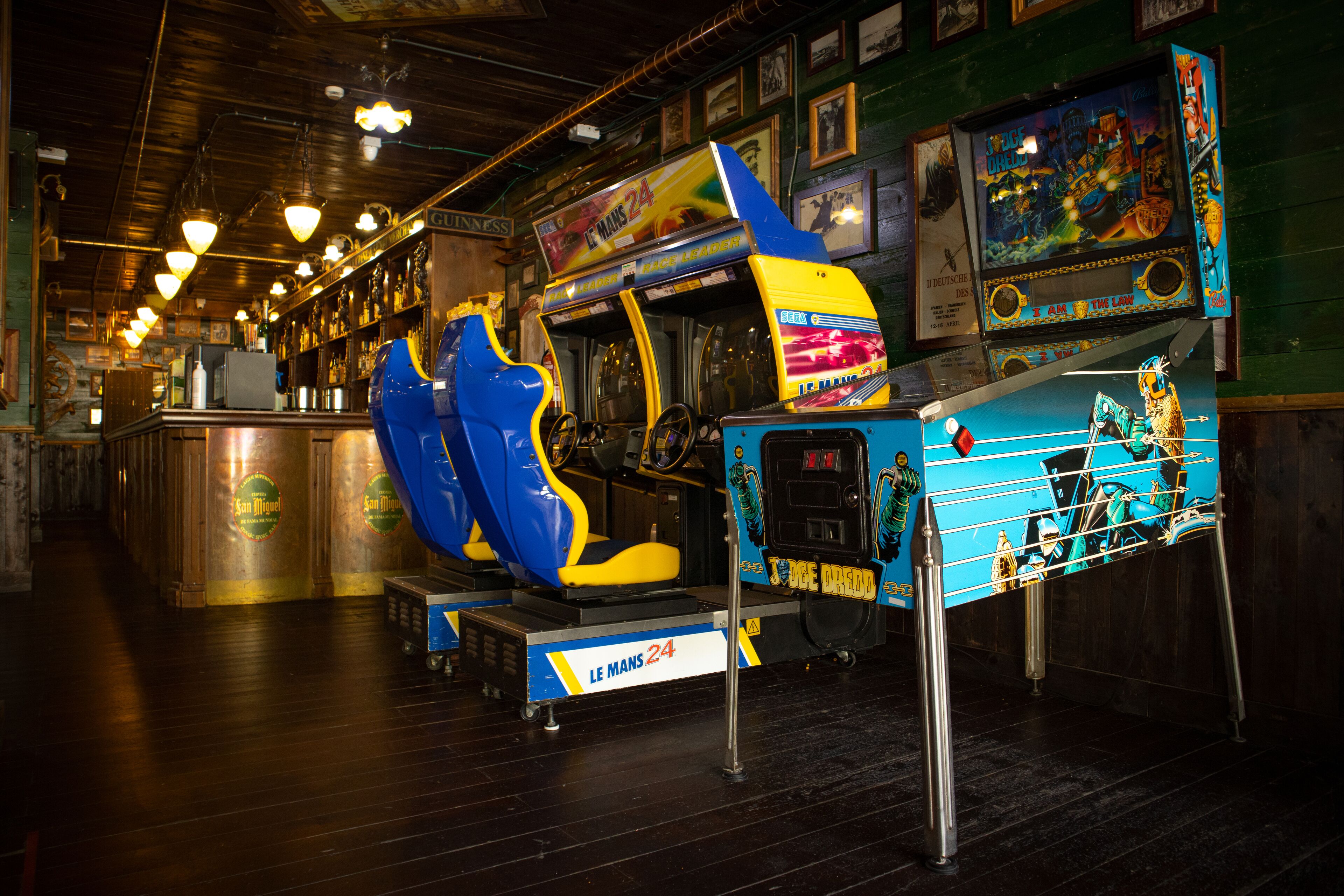 A bar area with arcade games, including a blue and yellow game and a blue game with a character on the screen.