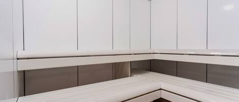 A sauna with white benches and a tiled floor.