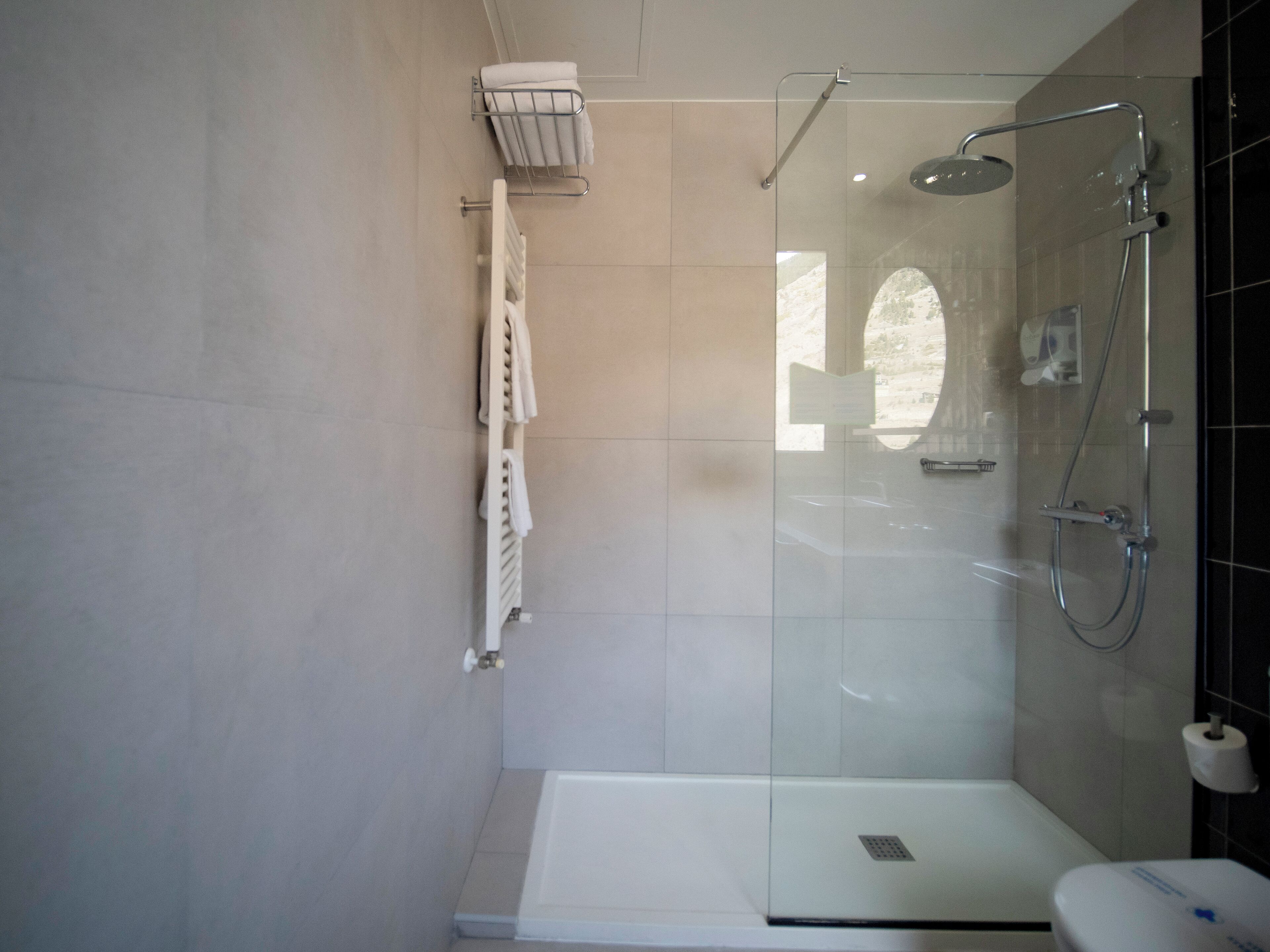 Un baño moderno con cabina de ducha de vidrio, inodoro blanco y barra para toallas.
