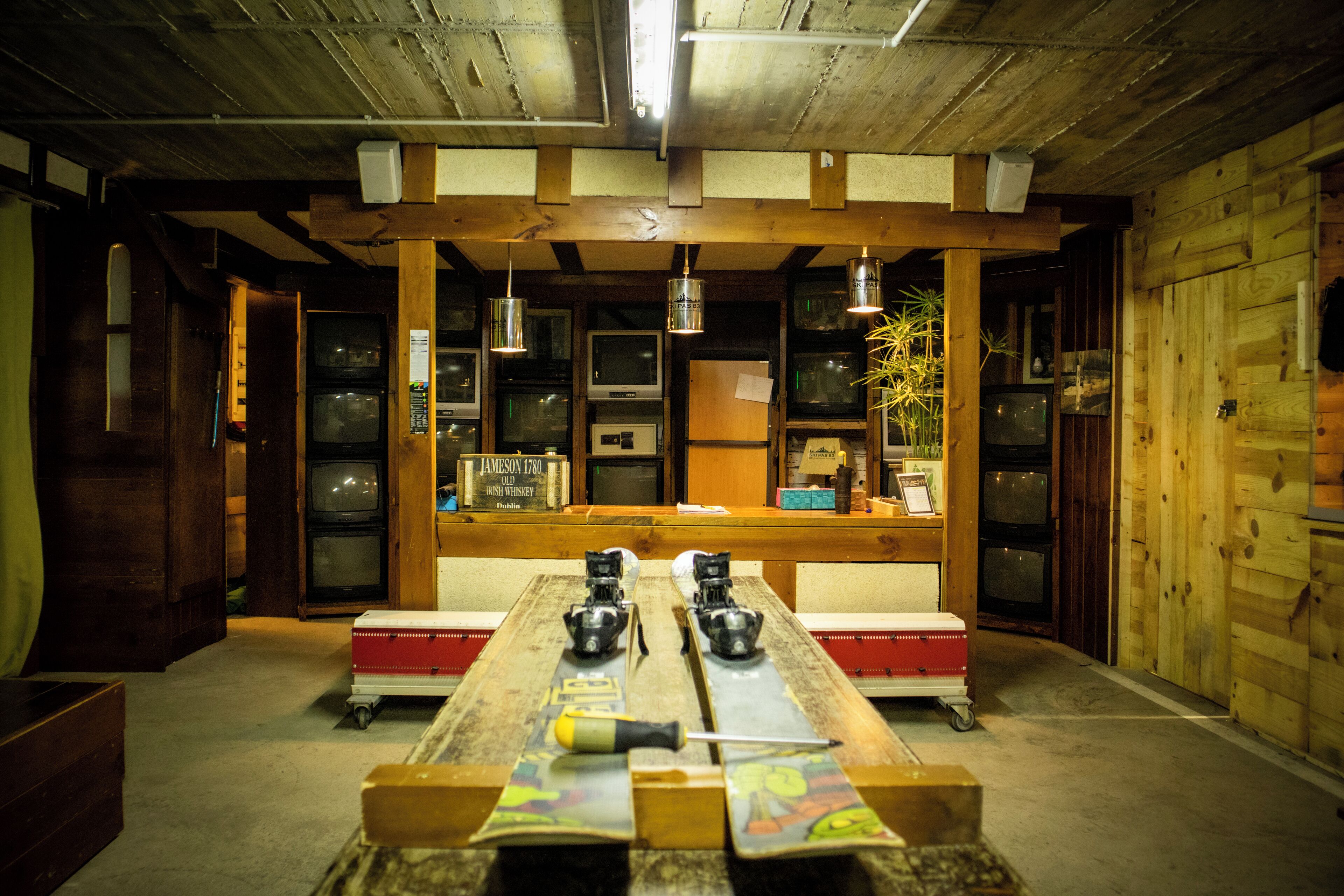 A room with a long wooden table, multiple televisions, and a wooden ceiling.