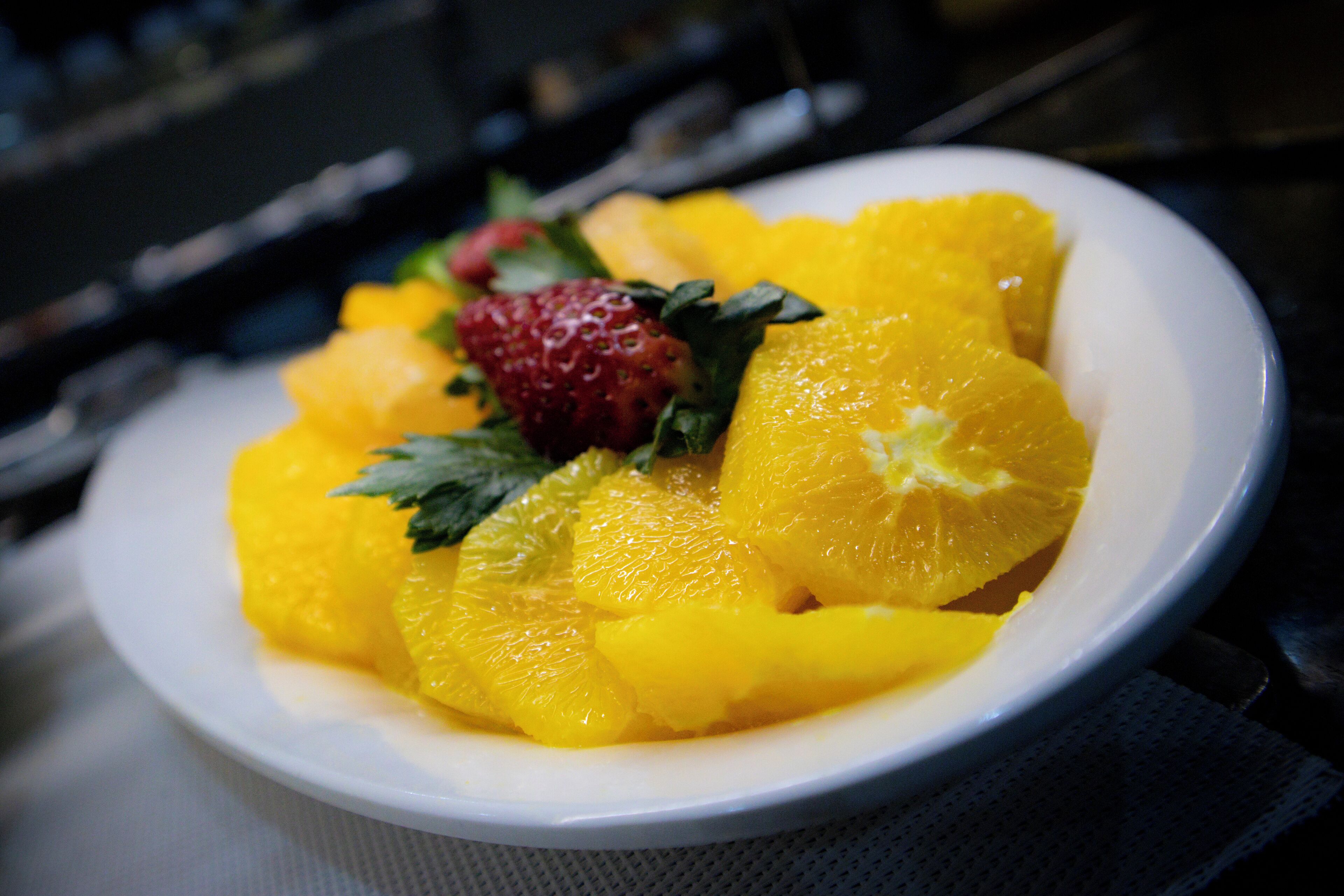 Un plato blanco con rodajas de naranja y una fresa.
