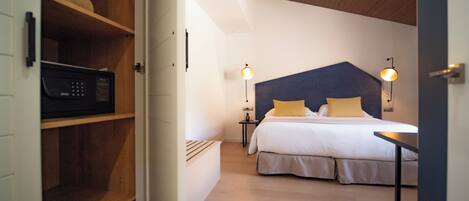 A bedroom with a bed, bedside lamps, a wooden shelf with a microwave, and a ceiling light.