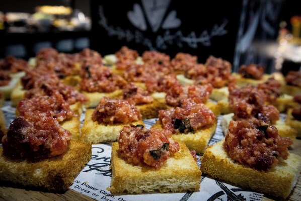 Una mesa con varios trozos cuadrados de pan cubiertos con una capa roja, posiblemente un paté o crema.