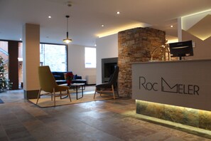 A lobby with a stone wall, a reception desk, and a seating area with chairs.
