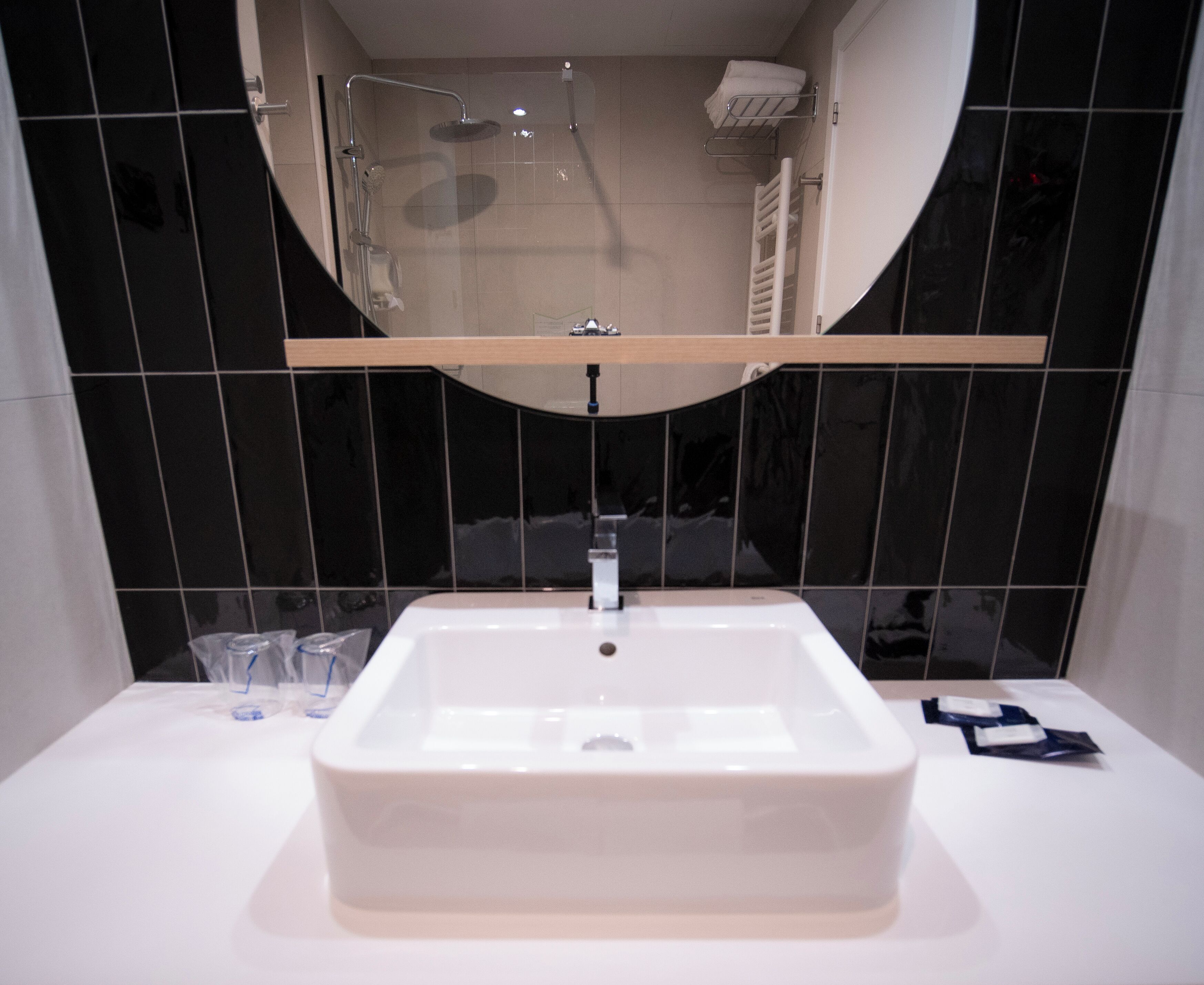 Une salle de bain avec un lavabo rectangulaire, un miroir au-dessus et une pomme de douche.
