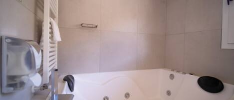 A modern bathroom with a large bathtub, a towel rack, and a hand dryer.