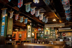 A restaurant interior with hanging decorations, wooden beams, and various signs on the walls.