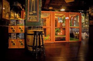 A bar area with wooden stools, a bar counter, and a wooden barrel. There are arcade machines and a sign that reads "Best quality and performance for the elite winter sports."