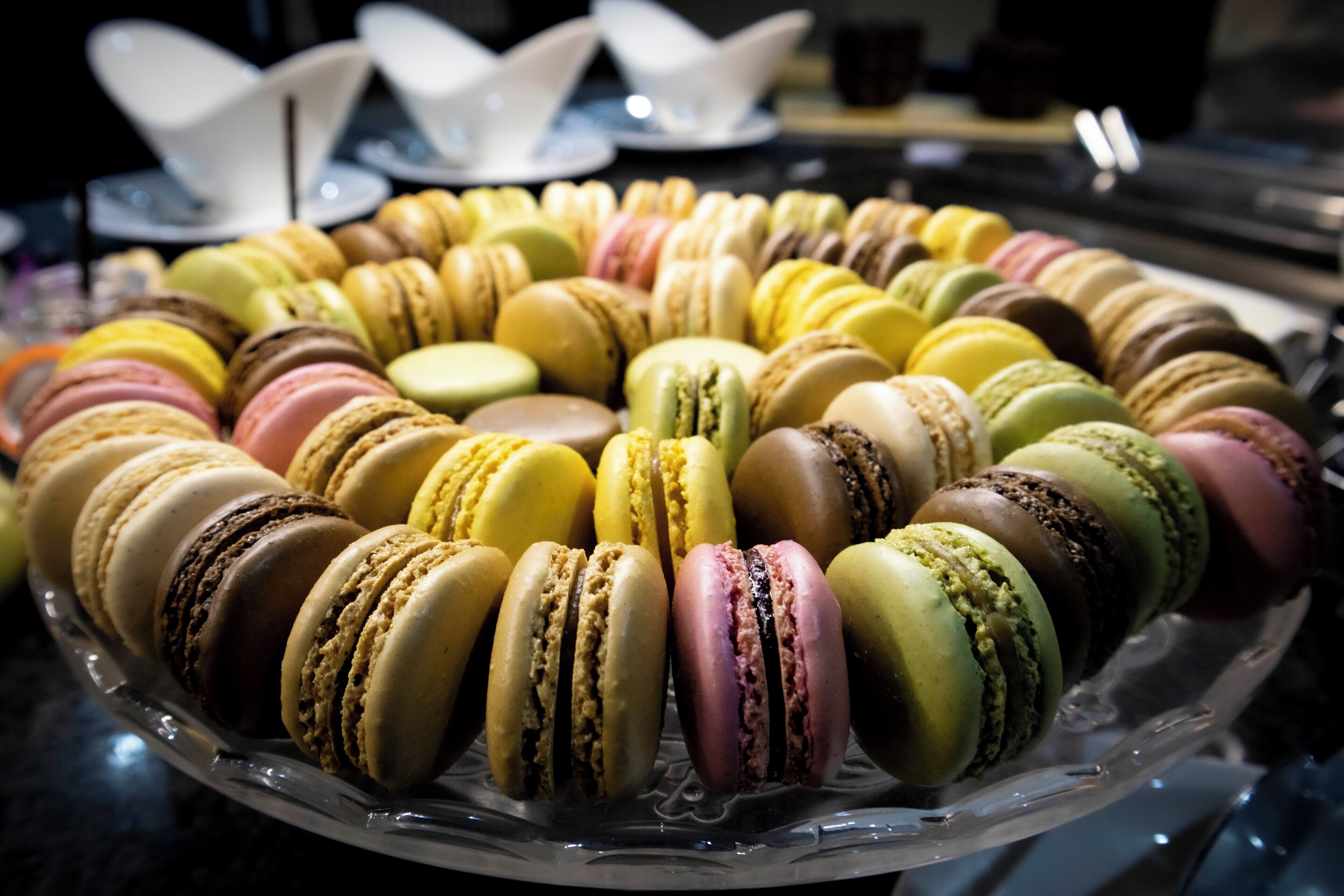 A glass display case filled with colorful macarons arranged in a circular pattern.