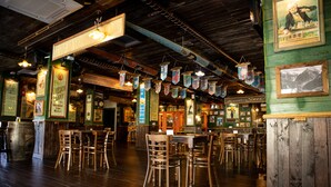 Un interior de restaurante con mesas y sillas de madera, decoraciones colgantes e imágenes enmarcadas en las paredes.