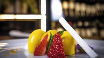 A dessert plate with yellow and red fruits and a white stick.