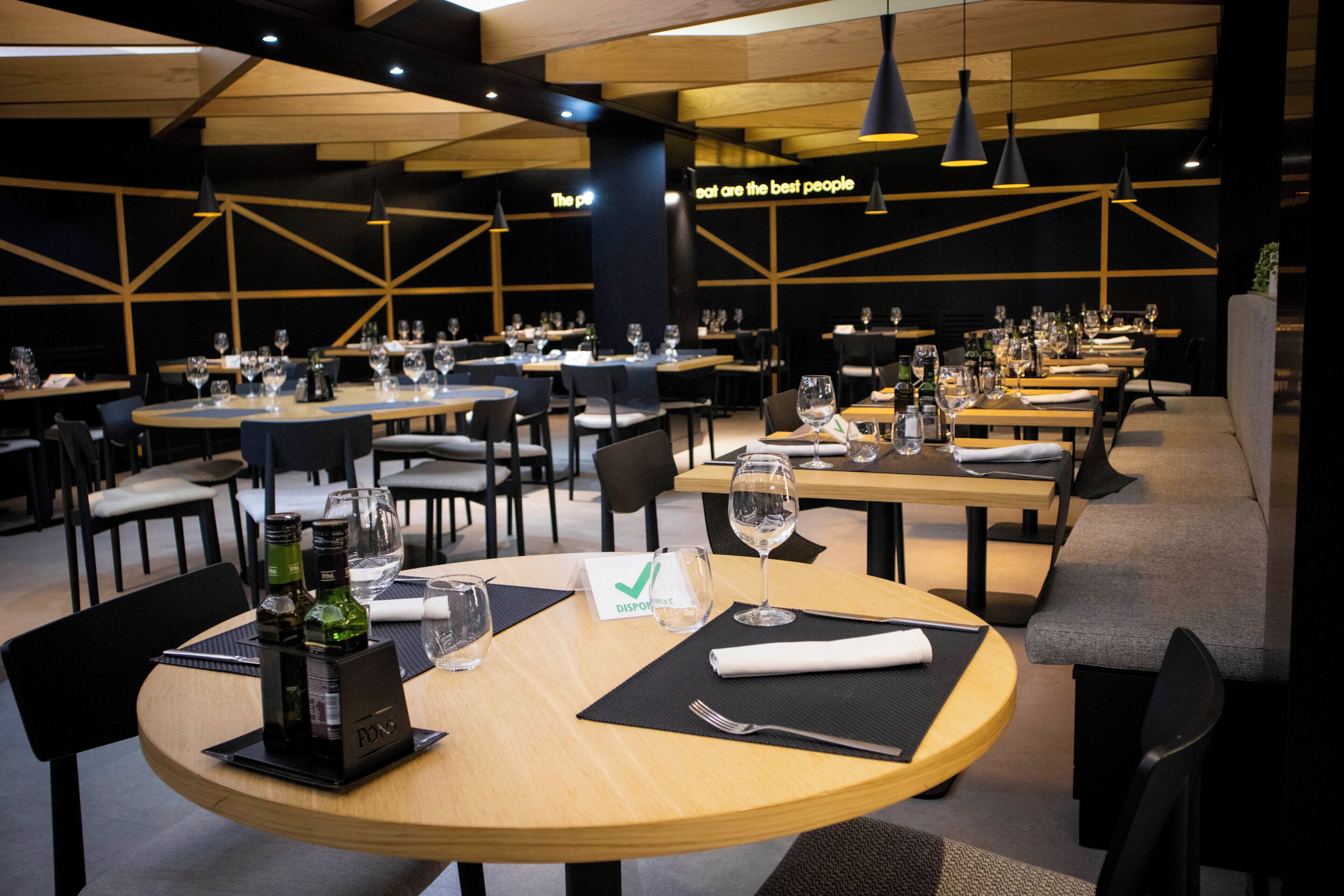 Een restaurant met ronde tafels, zwarte stoelen en een modern interieur.