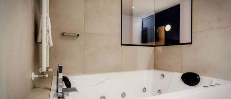 Un bagno moderno con una vasca da bagno ampia, uno specchio e un portasciugamani.