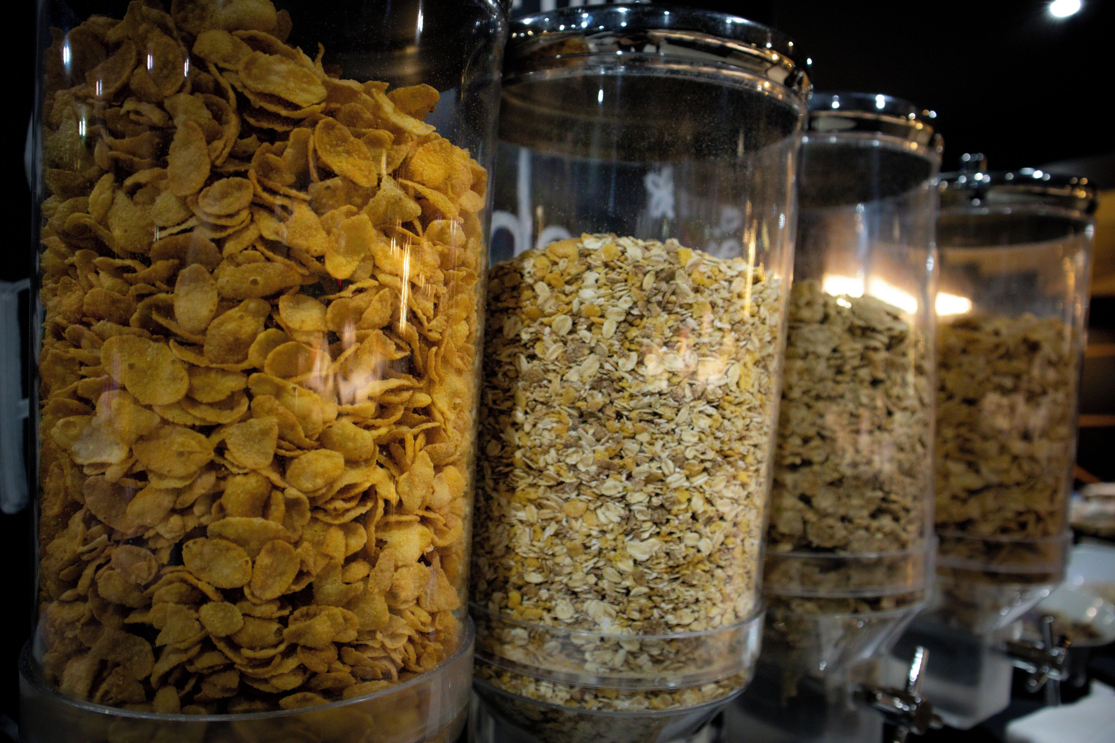 A row of transparent containers filled with various grains and cereal flakes.