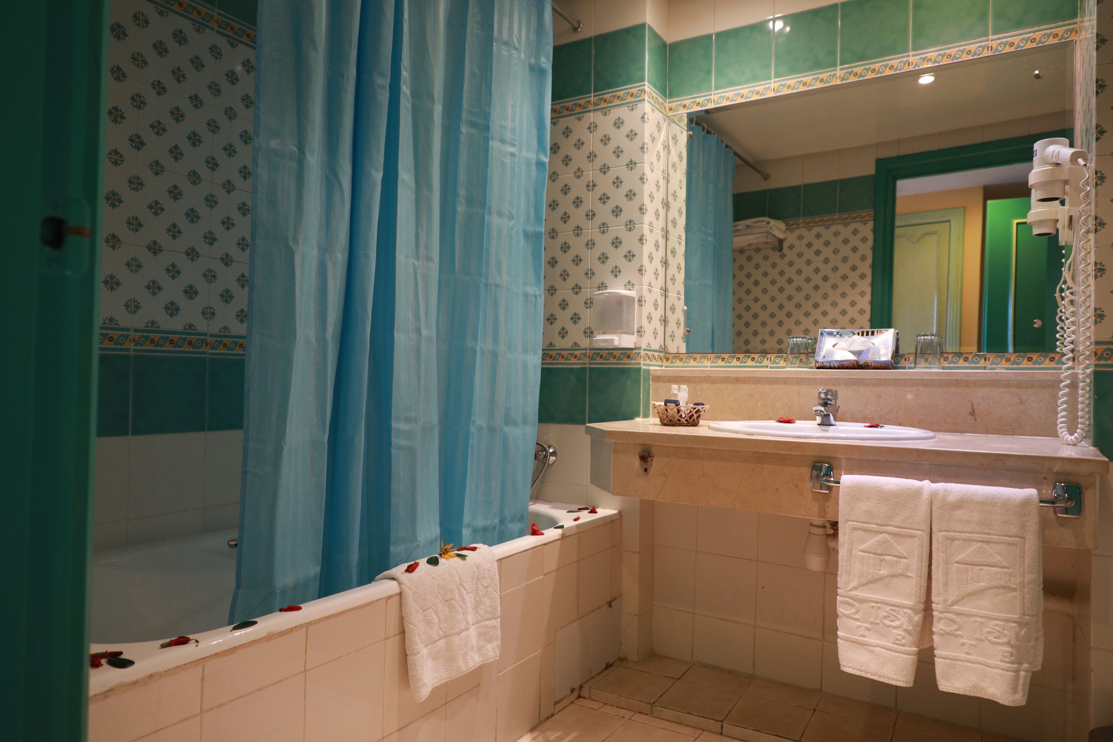 A bathroom with a bathtub, a sink, and a mirror.