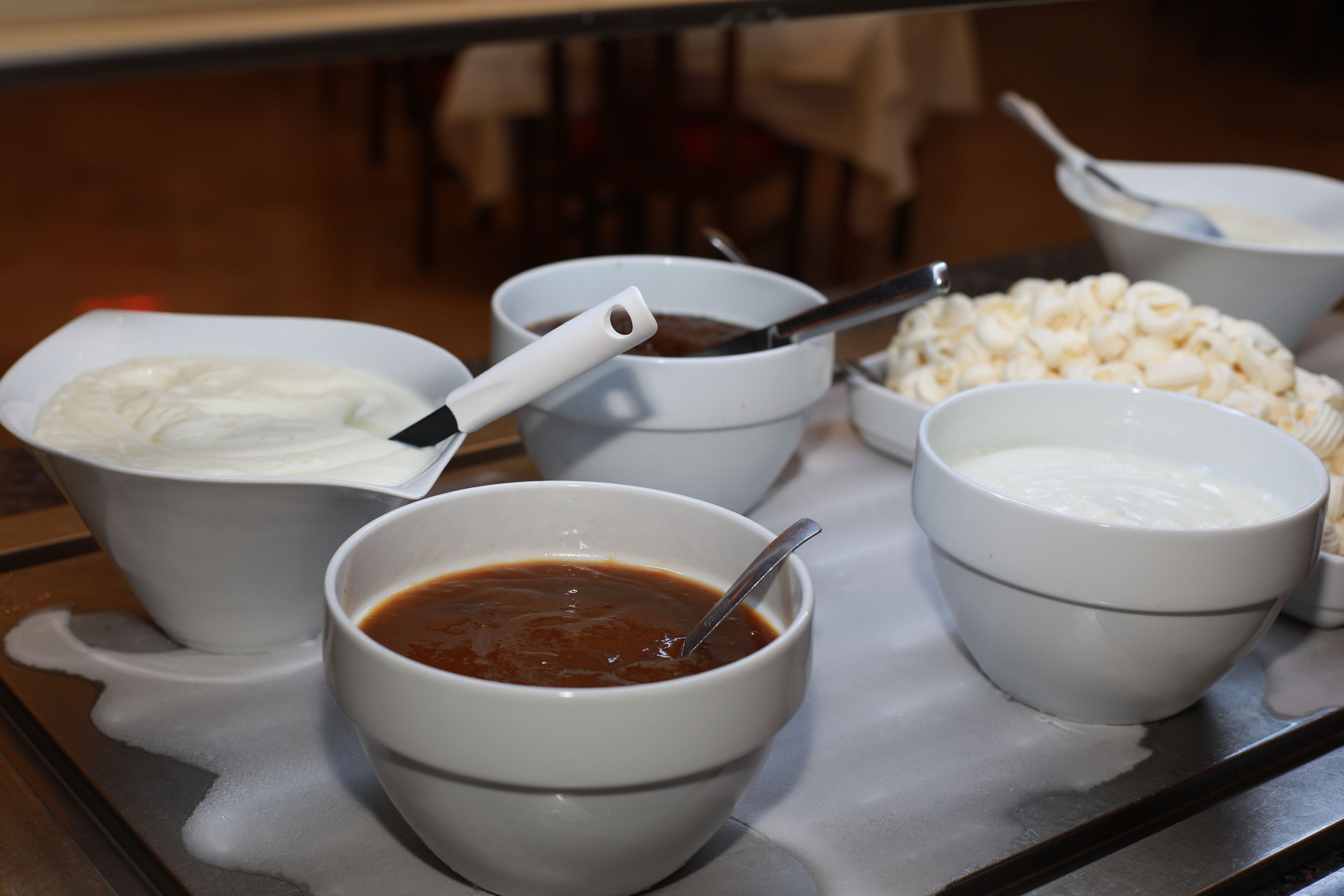 A tray with bowls containing various food items, including a bowl of soup, a bowl of yogurt, and a bowl of cereal.