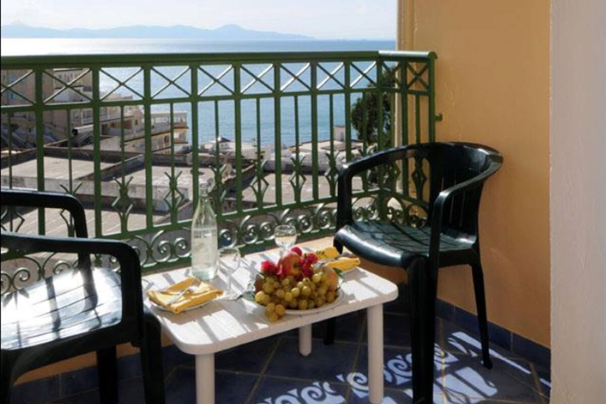 A balcony with a table, chairs, and a view of the sea.