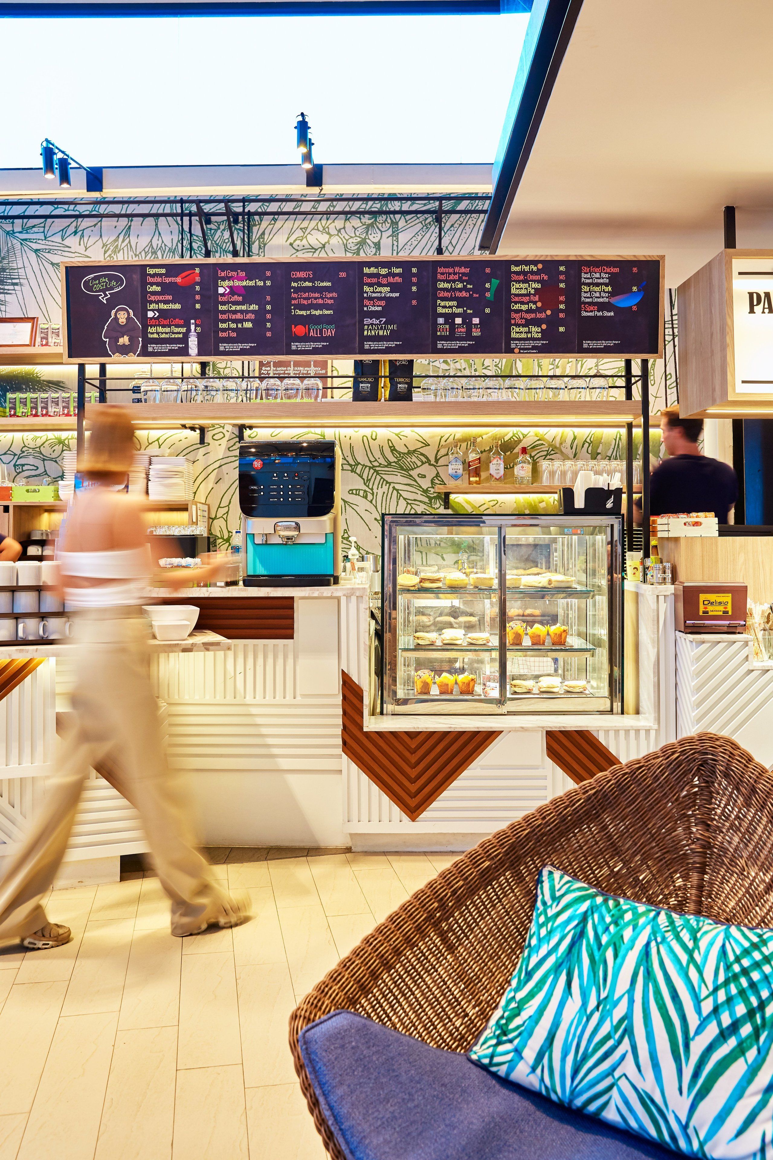 A cafe with a menu board, a coffee machine, and a display case with pastries.