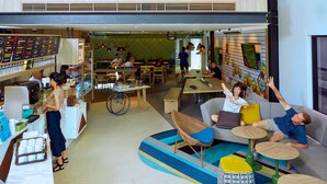 Un amplio espacio interior con un entrepiso, zonas de estar y una cafetería.