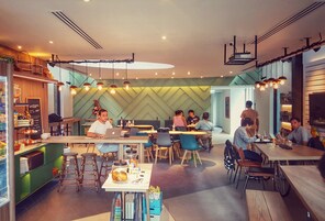 Ein modernes Restaurant mit mehreren Tischen, Stühlen, einer Bar und einer Theke mit Speisekarte.