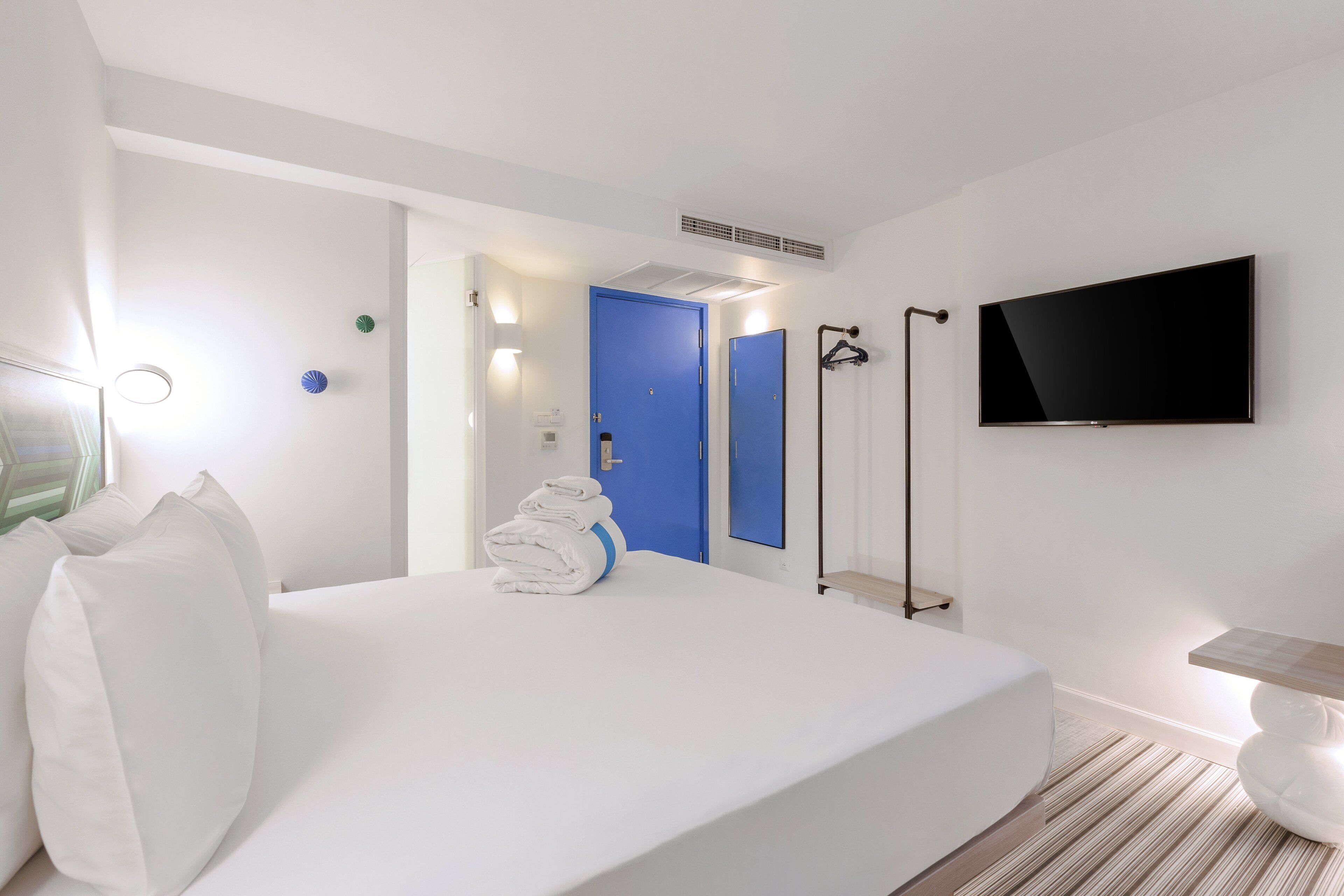 Habitació d'hotel amb un llit gran, televisió de pantalla plana, una porta blava i zona de banyera.