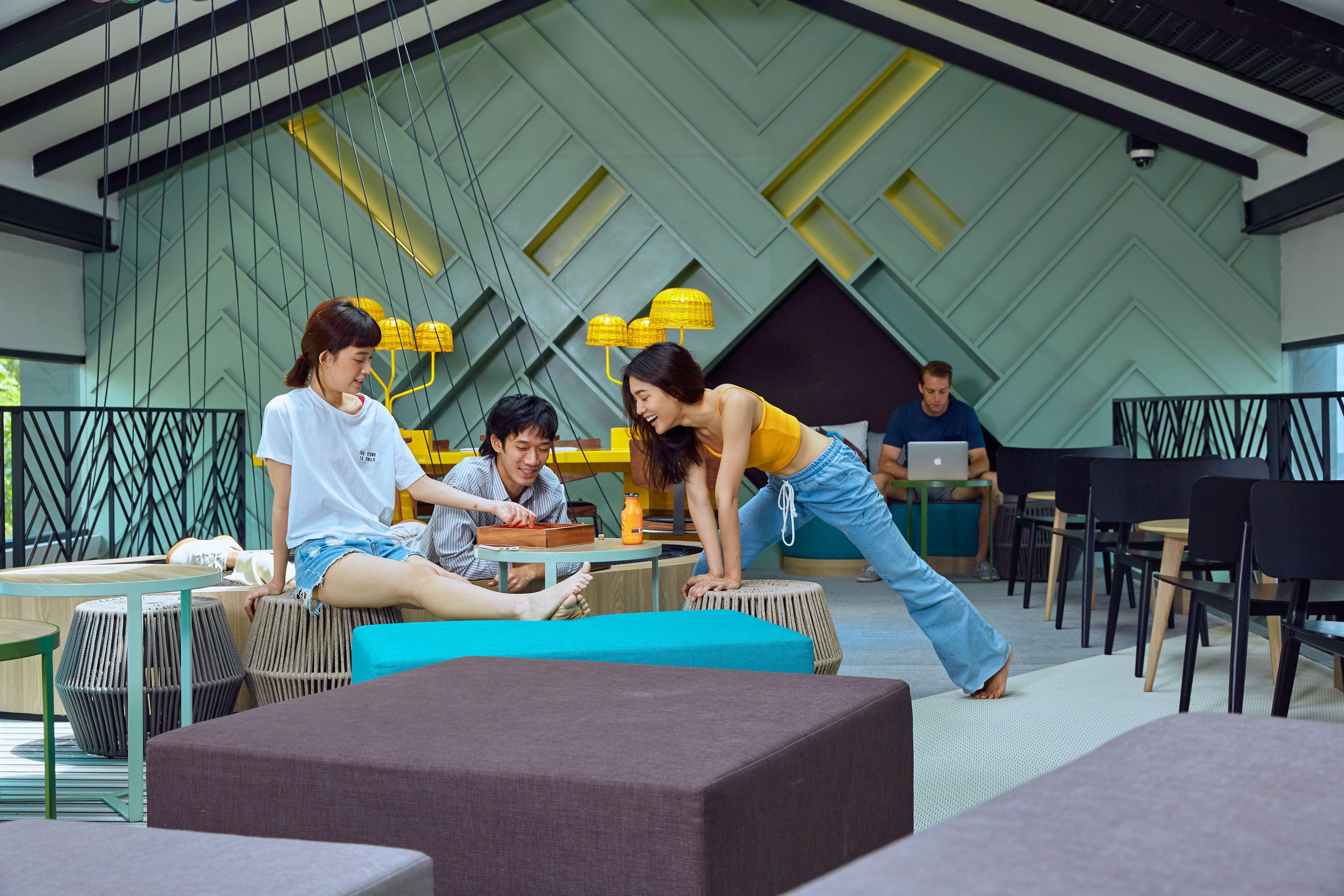 A modern indoor space with seating arrangements and tables, featuring geometric wall patterns and contemporary furniture.