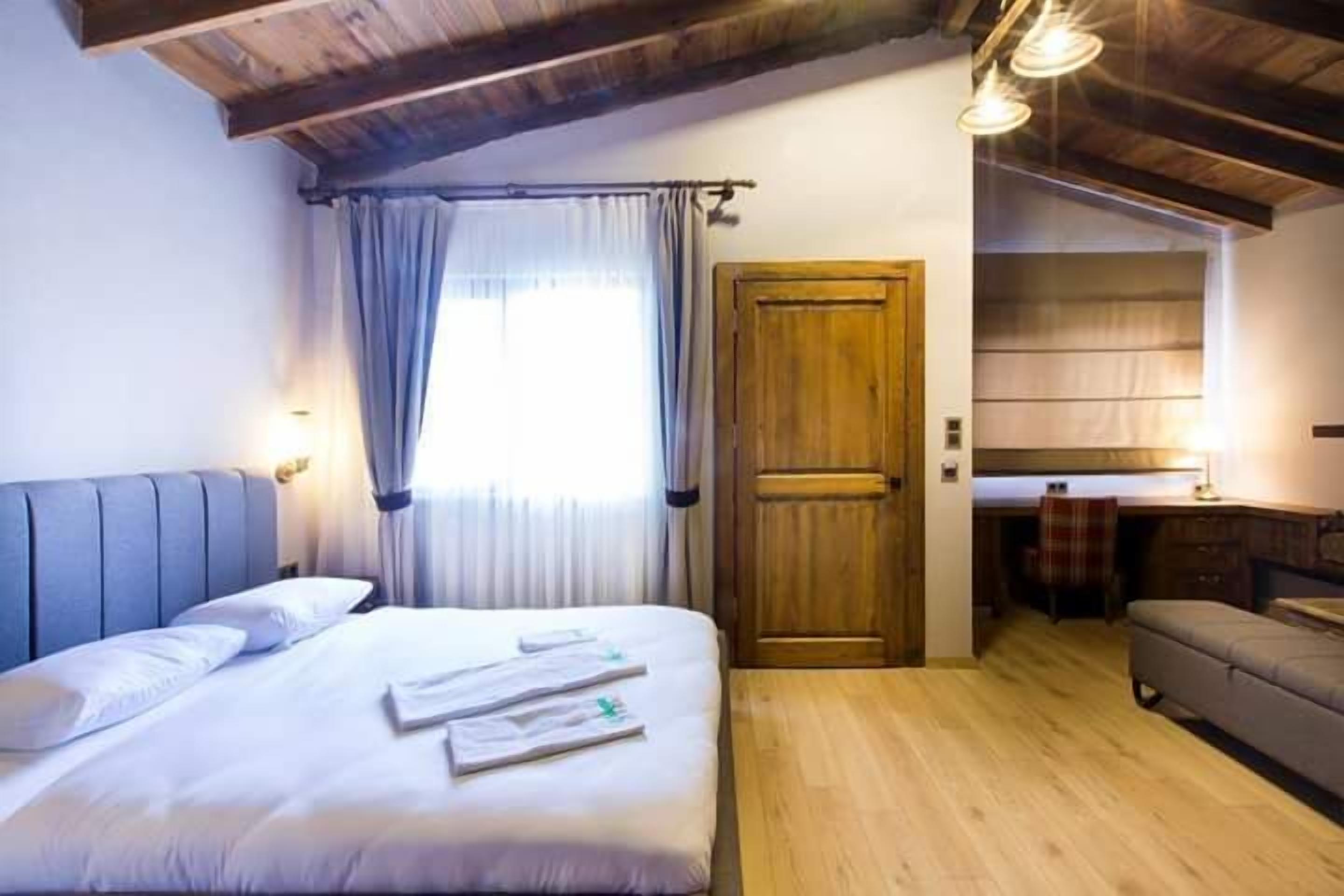 Un dormitorio con cama, una puerta de madera, una pequeña cocina y un sofá.