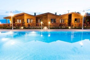 Un bâtiment de style cabane en bois, avec une piscine devant.