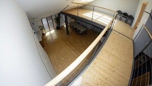 Ein geräumiger Loft mit hoher Decke, Holzböden, einem Essbereich mit Tisch und Stühlen sowie einem Balkon mit Geländer.
