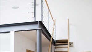 Ein modernes Interieur mit einer Holztreppe, einer Tür und einem Lichtschalter an der Wand.