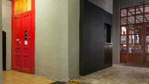 Un couloir avec une porte rouge et une pancarte indiquant la présence d’une auberge de jeunesse, posée sur le sol.