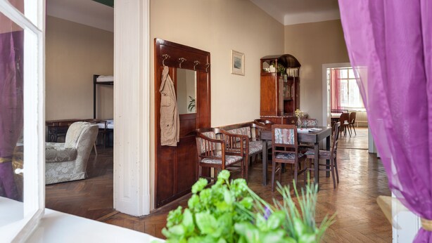 Un coin repas avec des meubles en bois, une porte blanche et une vue sur une chambre comprenant un lit et une chaise.