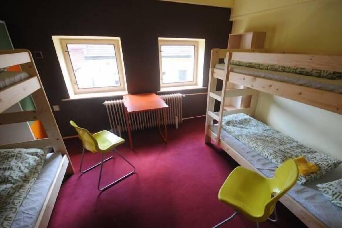 Une chambre de dortoir avec des lits superposés, un bureau et deux chaises.