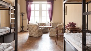 Une chambre de dortoir avec des lits superposés, un ensemble de canapés, une table et une fenêtre avec des rideaux.
